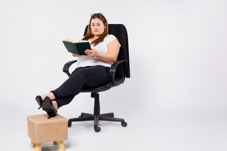 Young overweight woman accountant in glasses working in office, making notes in diary, filing taxes, providing outsource accounting service.の写真素材