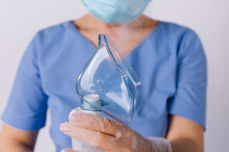 Cropped photo. Doctors hands holding a respiratory mask on a white background. Respiratory and allergy treatment.の写真素材