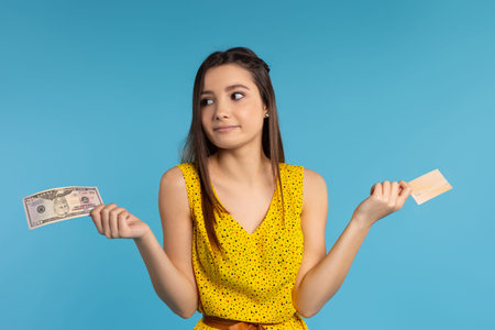 Woman choosing between bank card and cash money. Budget planning concept. Money savings investment...