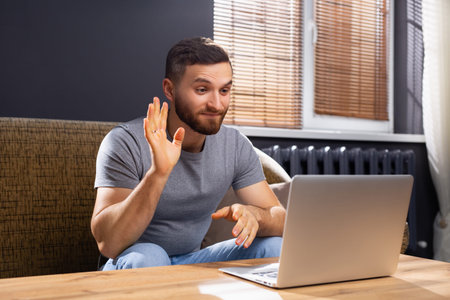 Young man online communication. He makes videocall chat talking with relatives or friends by video...