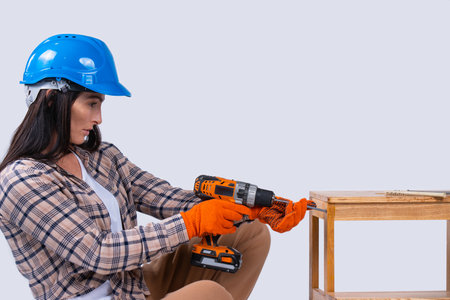 Female carpenter drills a hole with an electrical drill. Repair and renovation concept. Woman repair tools for house constructor. Cordless drill, screwdriver with drillsの写真素材