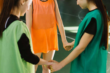 Happy young girls talking in sport gym before training. Female basketball players standing in court. Cropped photo of coach advising female players while practicing indoor gameの写真素材