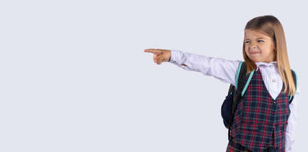 Banner, long format, grey background. Upset schoolgirl pointing her finger to side, away. Serious girl showing exit, asking to leave her alone. Get out, Get off.の写真素材