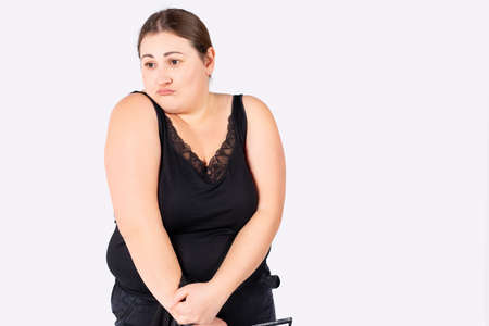 Portrait of a chubby disgruntled woman in casual wear against a white background with side space. Excess weight.の写真素材