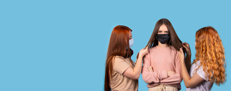 Banner,long format. Three young female friends with long hair and protective masks againstの写真素材