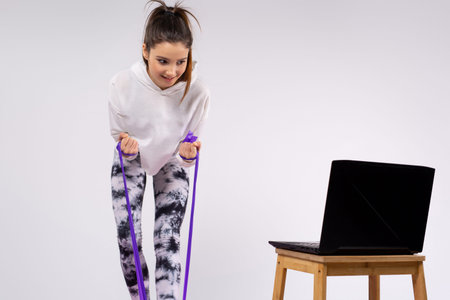 Sports at home. The tight, athletic body of the girl with an elastic band does exercises for all...