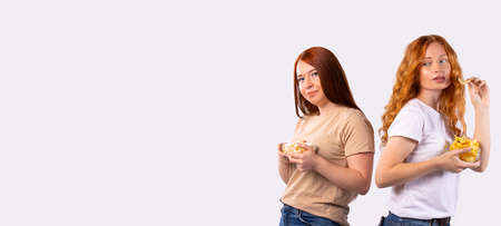 Girls pose with plates full of potato chips on a long banner with a white photo. Empty side space for text or advertisements.の写真素材