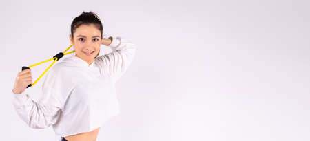 Banner, long format. Young athletic girl with drag rope elastic band on white studio background with side space for text or advertising. High quality photoの写真素材