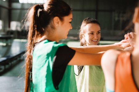 Young beautiful group of sportswomen standing shaking hands after class of sport training at gym. Strong team spirit. High quality photoの写真素材