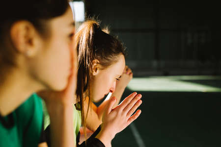 Football fans praying indoors gym. Pleading girls, football fans with closed eyes support favorite team putting hands together praying. People emotions, sport family leisure. High quality photoの写真素材