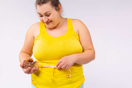 A cheerful and full-mouthed woman, full of size, full of food, holding a plate of something tasty and eating, imitates her training. High quality photoの写真素材