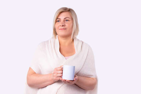Portrait of a beautiful woman dressed in a white cardigan holding a cup of tea in beauty skin care salon. High quality photoの写真素材