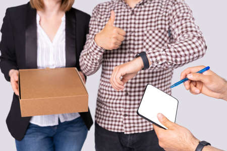 A young couple is very happy the courier delivered a package on time so they need to sign for it on the tablet. . High quality photoの写真素材