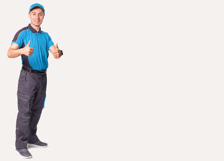 Delivery concept - portrait of happy delivery man standing and showing thumbs up for successful parcel deliveryの写真素材