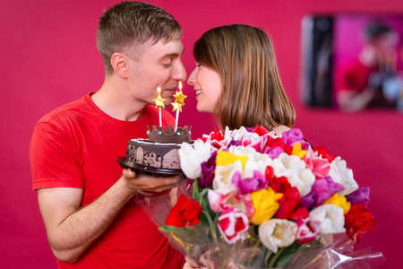A young beautiful couple celebrate the consent of the bride with torte and a huge bouquet of flowers.の写真素材