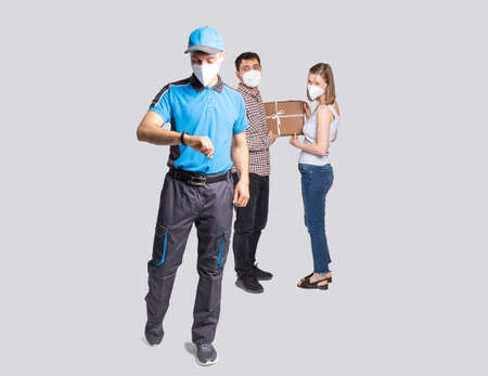 Delivery man employee in blue uniform and face mask delivered the package and he is in a hurry to deliver another goods.の写真素材