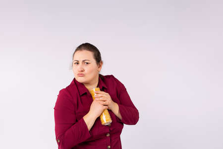Photo of a one serious fat woman in red dress holding packaging biscuits in her hands so no one can take it.の写真素材
