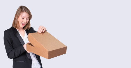 Young business woman in a white blouse and black jacket receives a package so she is very happy while opening it.の写真素材