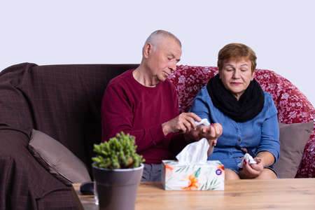 Considerate husband measures wife temperature putting a thermometer on her hand and so she uses handkerchief.の写真素材