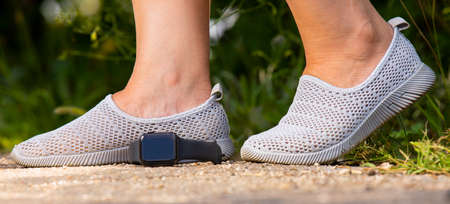 Close up image of the legs of woman in comfortable shoes for jogging outdoors and digital watch lies on the ground.の写真素材
