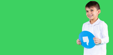 Smiling schoolboy in uniform holding in his hands circle blue color with the sign thumb down on it.の写真素材