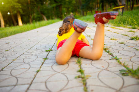 The back view pose of a girl lying on the stomach side on the path in the park raised her legs up bent at the knees.の写真素材