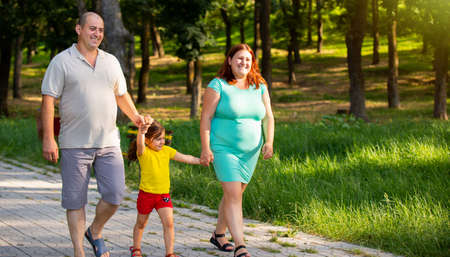 Beautiful nice health family of three walking together in the park spending the time being in a excellent mood, they smiling.の写真素材
