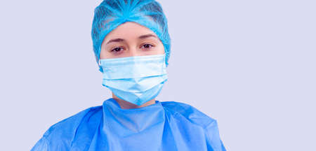 Exhausted medical personal in blue uniform and in a mask posing on a camera looking very tired.の写真素材