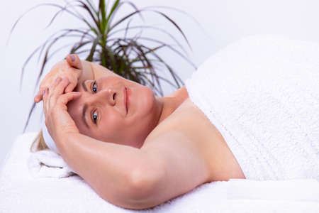 Comfortably lying woman on a massage table in a beauty salon expecting for a specialist to appear in the cabinet.の写真素材