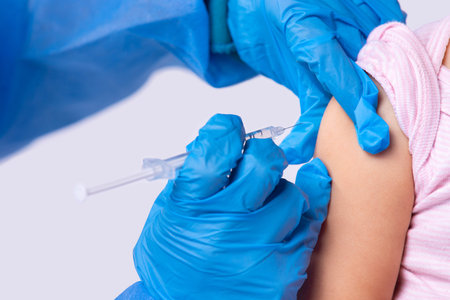 Cropped photo of a doctor in rubber gloves giving vaccination to a little girl