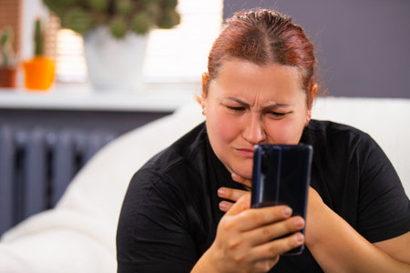 Photo of sensitive woman sitting can not leave the phone, she is addicted to look the bad news or information.の写真素材