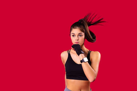 Athletic young girl with intent look posing on the camera wearing black short top keeping her hand at the chin.の写真素材