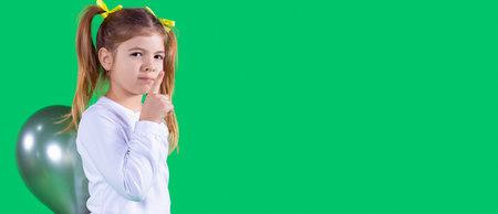 Nice pretty girl making silence gesture with the notice finger and holding the green balloon behind...