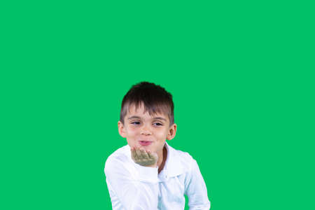 The nice young boy in white t-shirt sending an air kiss holding his hand near mouth in a excellent mood.の写真素材
