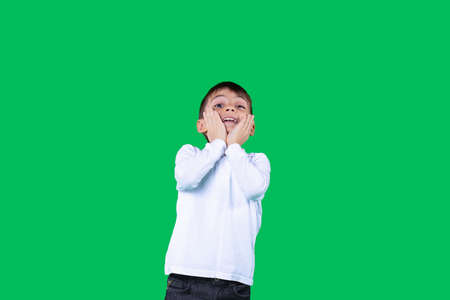 The boy holding his face with the hands looking up emotionally with facial expression looking up.の写真素材