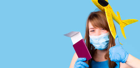 Happy woman with smiling eyes in a medical mask and gloves holdings passport and the ticket for the journey in pandemic time.の写真素材