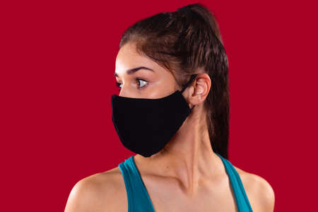 Close up photo of a nice young girl wearing the textile mask of black color turned her head to the right side.の写真素材