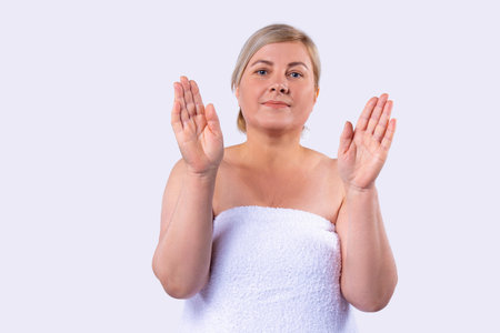 Shy blonde woman shows and advertises some product for the hand skin care holding her hands up turned palms to the camera.の写真素材