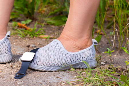 The close up photo of the legs of a fitness woman in the summer moccasins with digital watch fell on her one foot while she was practicing sport.の写真素材