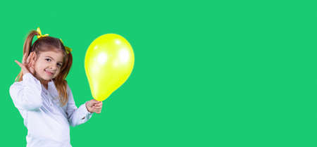 little girl in white t-shirt holding an inflatable balloon yellow color is getting ready for a party time.の写真素材