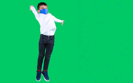 Boy in the school uniform and blue textile mask on break time in the school jumping for joy.の写真素材