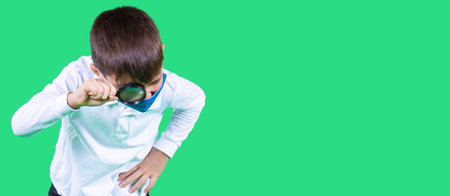 School age boy in a medical face mask blue color looking at an object with a magnifying glass holding in his hand.の写真素材