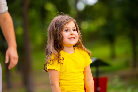 Close up photo of a smiling little girl satisfied of being with her dad in the park, they spend nice...