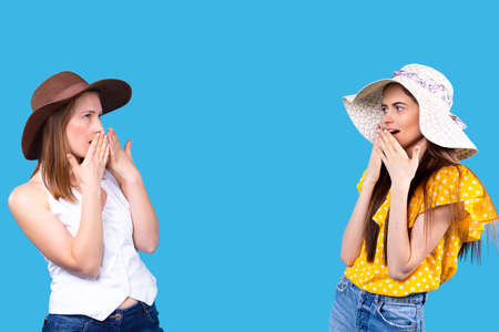 Adorable astonished girl on summer vacation stand opposite each other covering the mouth with the hands.の写真素材