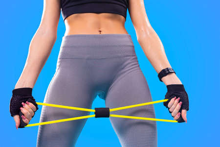 The photo of sweaty pretty young woman with wet muscle body in leggings practicing fitness with sports rubber.の写真素材