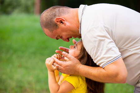 Father and daughter spending a good sunny day together, daddy is looking from above at his little daughter with smiling face and she is holding his hands.の写真素材