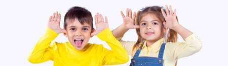 Banner, long format. Two children boy and girl having fun in front of the camera, they grimacing and the boy showing his tongue.の写真素材
