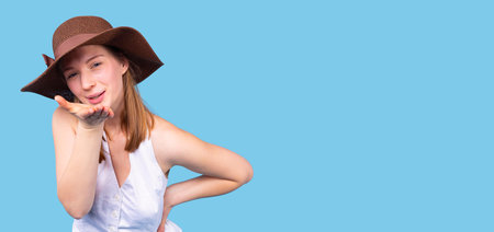 Self content young pretty woman in white top wearing the hat brown color with the bow is blowing a kiss.の写真素材