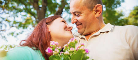 Close up photo of a pretty lovely couple having a date looking at each other with a smile facial expression and woman holding flowers.の写真素材
