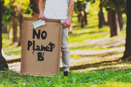 Climate change manifestation poster No Planet B holding by a man and keeping in his hand a medical mask protesting to save planet earth.の写真素材